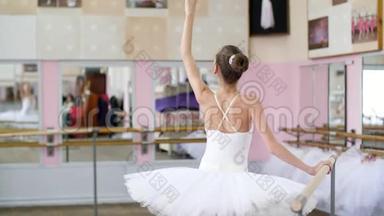 在芭蕾舞厅里，穿着白色芭蕾舞裙的女孩，包在芭蕾舞中，排练弯曲背部，倾斜背部，年轻